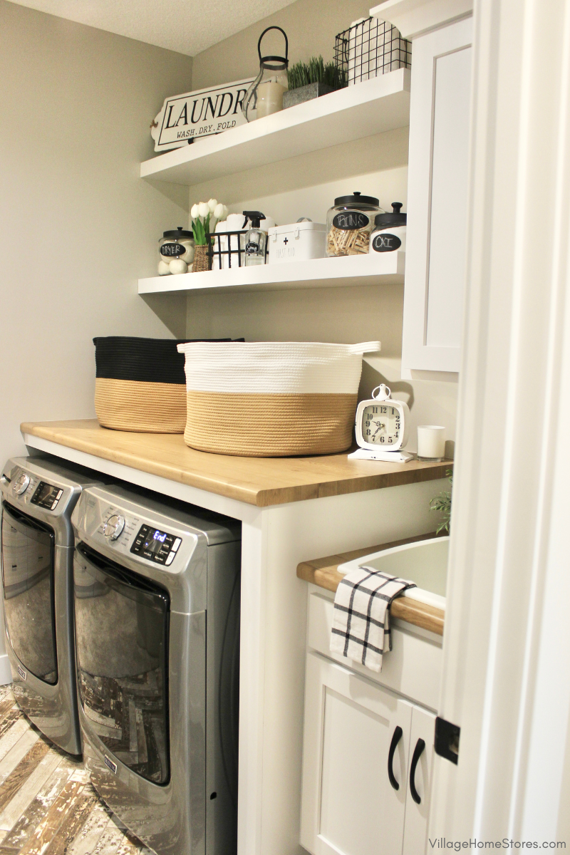 Laundry rook workstation with Maytag front load laundry, folding counter, floating shelves, and sink. Cabinetry, counters, and laundry appliances by Village Home Stores