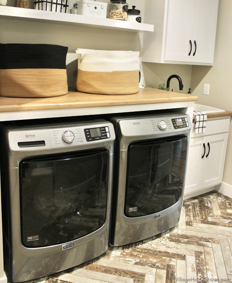 Laundry rook workstation with Maytag front load laundry, folding counter, floating shelves, and sink. Cabinetry, counters, and laundry appliances by Village Home Stores