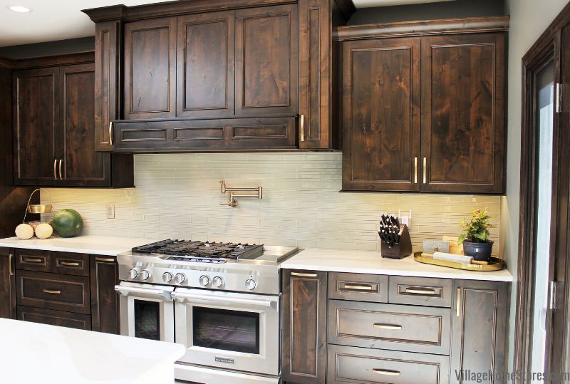 Kitchen cooking zone wall with 48 inch wide stainless steel KitchenAid gas range and pot filler on tiled wall.