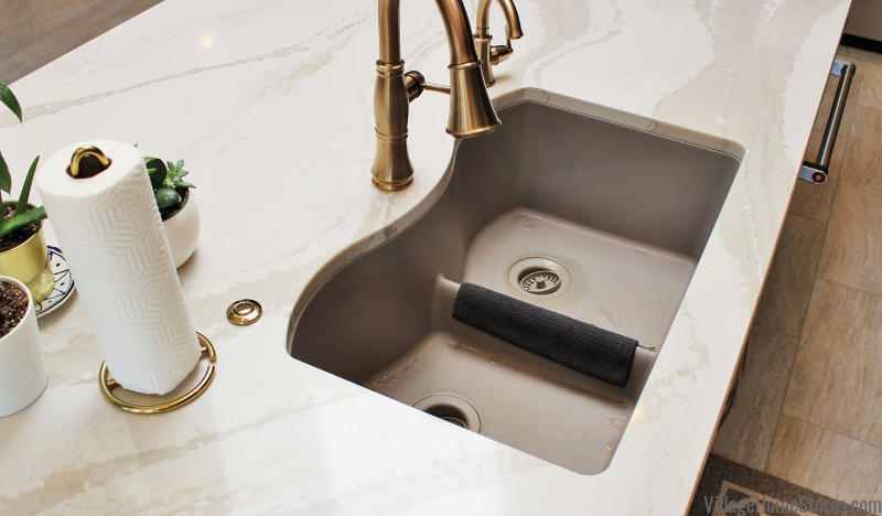 Brittanicca Warm Cambria counters and dove gray colored undermount sink with low divider double-bowl layout.