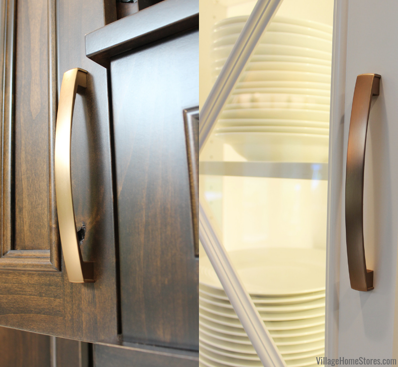 Merrick style handles in soft gold finish shown on dark stained cabinet door and painted white doors side by side.