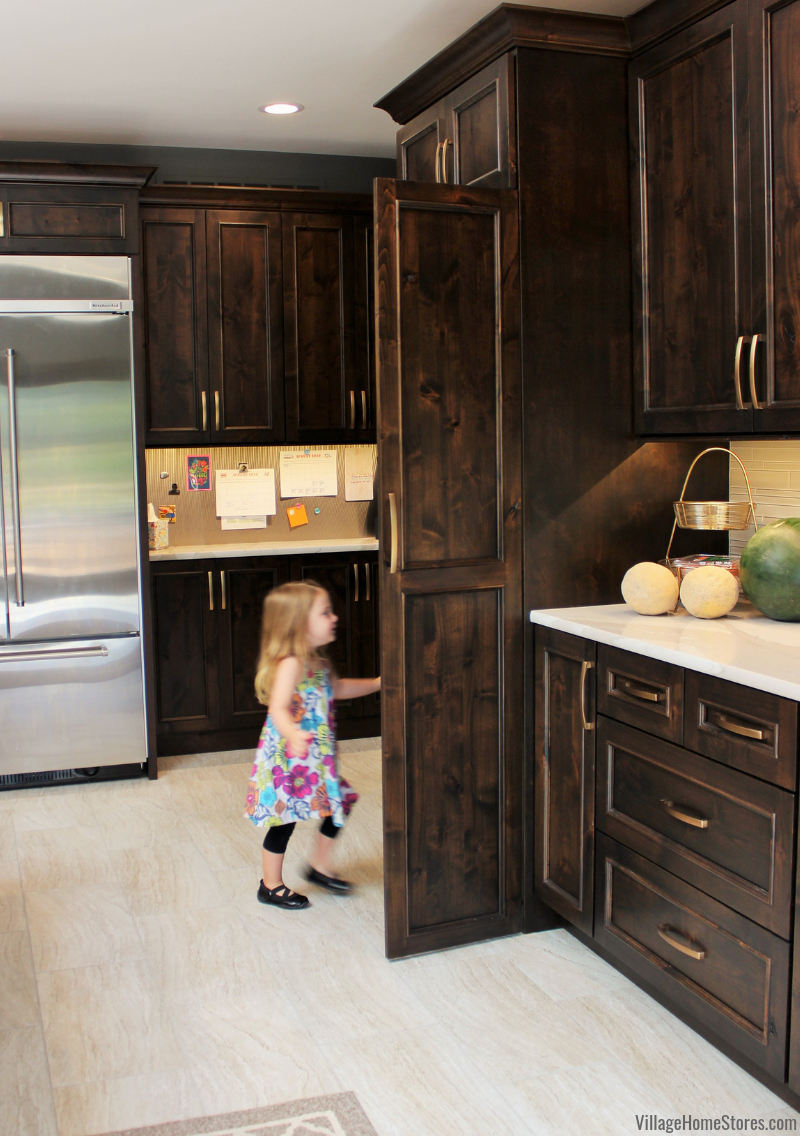 Tall pantry cabinet front with doors open and little girl walking in