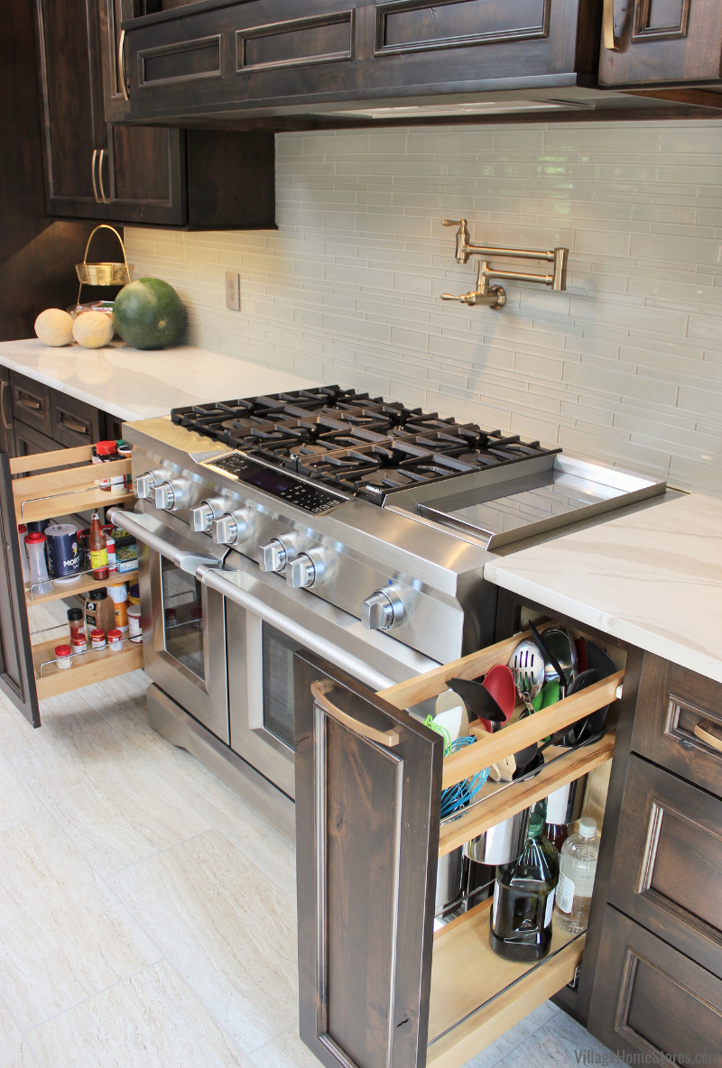 Large commercial style stainless range surrounded by two pullout cabinets shown open: pullout spice cabinet on left, and pullout utensil caddies on the right.