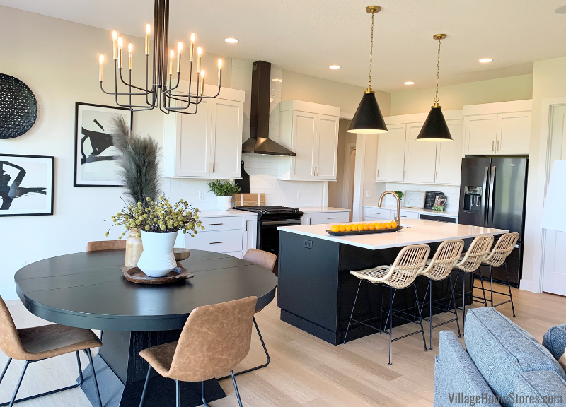 Image of white painted kitchen with black island and round dining table nearby. 