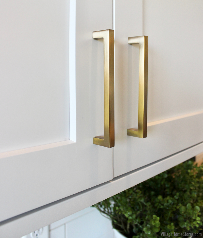 White cabinet detail image with two brushed gold finish handle installed. Stanton series handles by Jeffery Alexander available from Village Home Stores.