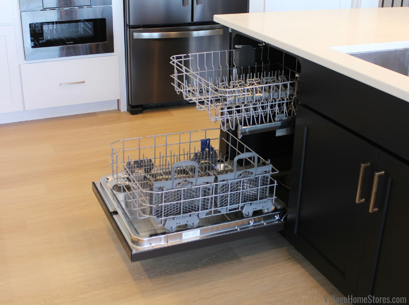 Image of whirlpool dishwasher installed in a black cabinet island. Door to dishwasher is open with empty racks rolled out. 