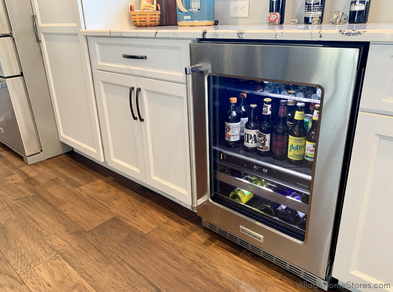 Glass-front Kitchen Aid beverage cooler with wine and beer displayed inside.