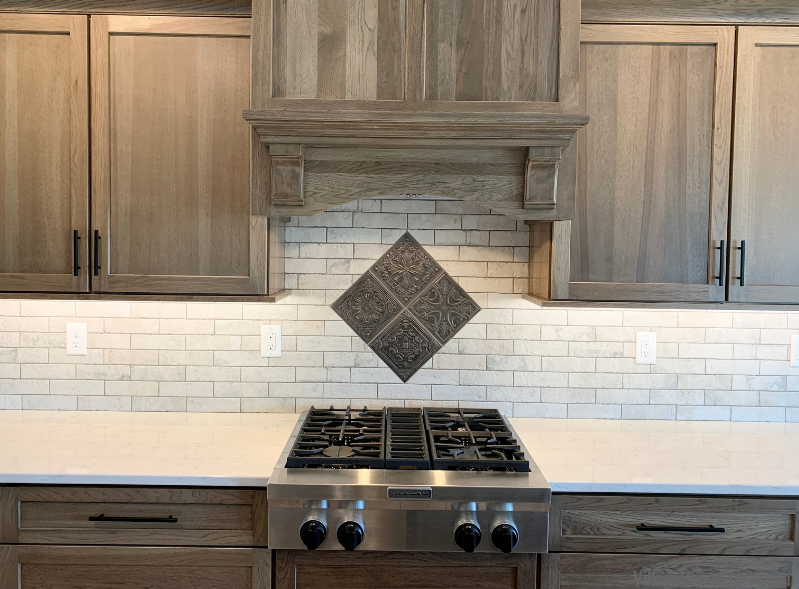 Kitchen backslash with metal tin tile look accent area above cooktop.