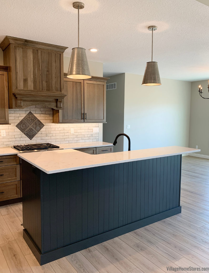 Dark painted Graphite kitchen island with tall bar-height beadboard backing. Two metal pendant lights hang above kitchen island. 