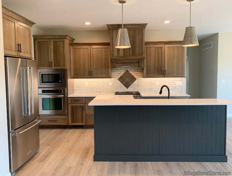 Kitchen design with warm Morel stained Hickory Dura Supreme cabinets ad painted Graphite Island. Two metal pendants hang above.