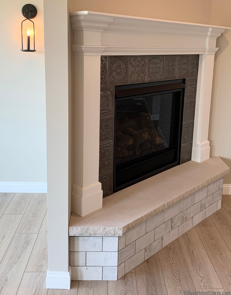 Fireplace with white painted mantle and tin look tile surround.