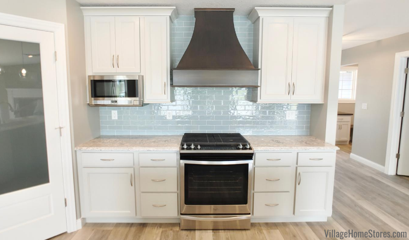 Kitchen wall with Stainless Steel range, painted white cabinets, and blue wall tile