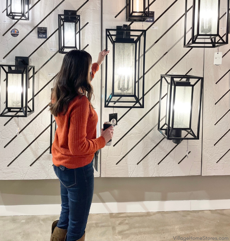 woman in sweater standing by large outdoor lantern light fixture