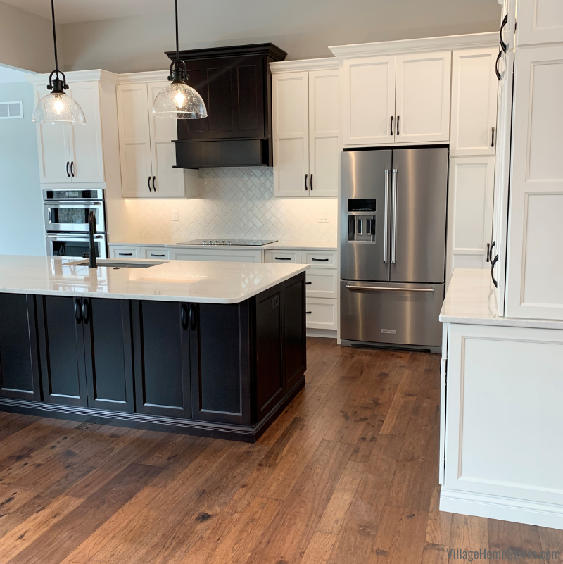 Great Room kitchen featuring Koch Classic Cabinetry in Ivory Paint with a Birch Java island. Stainless Steel KitchenAid appliances, Cambria Quartz Ironsbridge countertops, and seedy glass matte black pendants are also featured.
