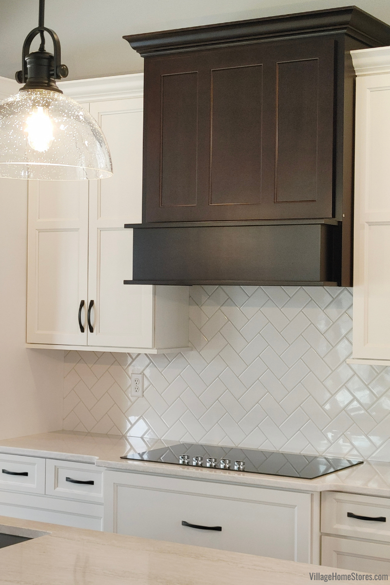 Birch Java wood range hood above KitchenAid electric cooktop. Arctic White subway tile installed as backsplash with Cambria Quartz Ironsbridge countertops.