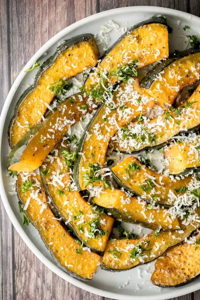 Overhead shot of acorn squash in crescent slices dusted with parmesan cheese
