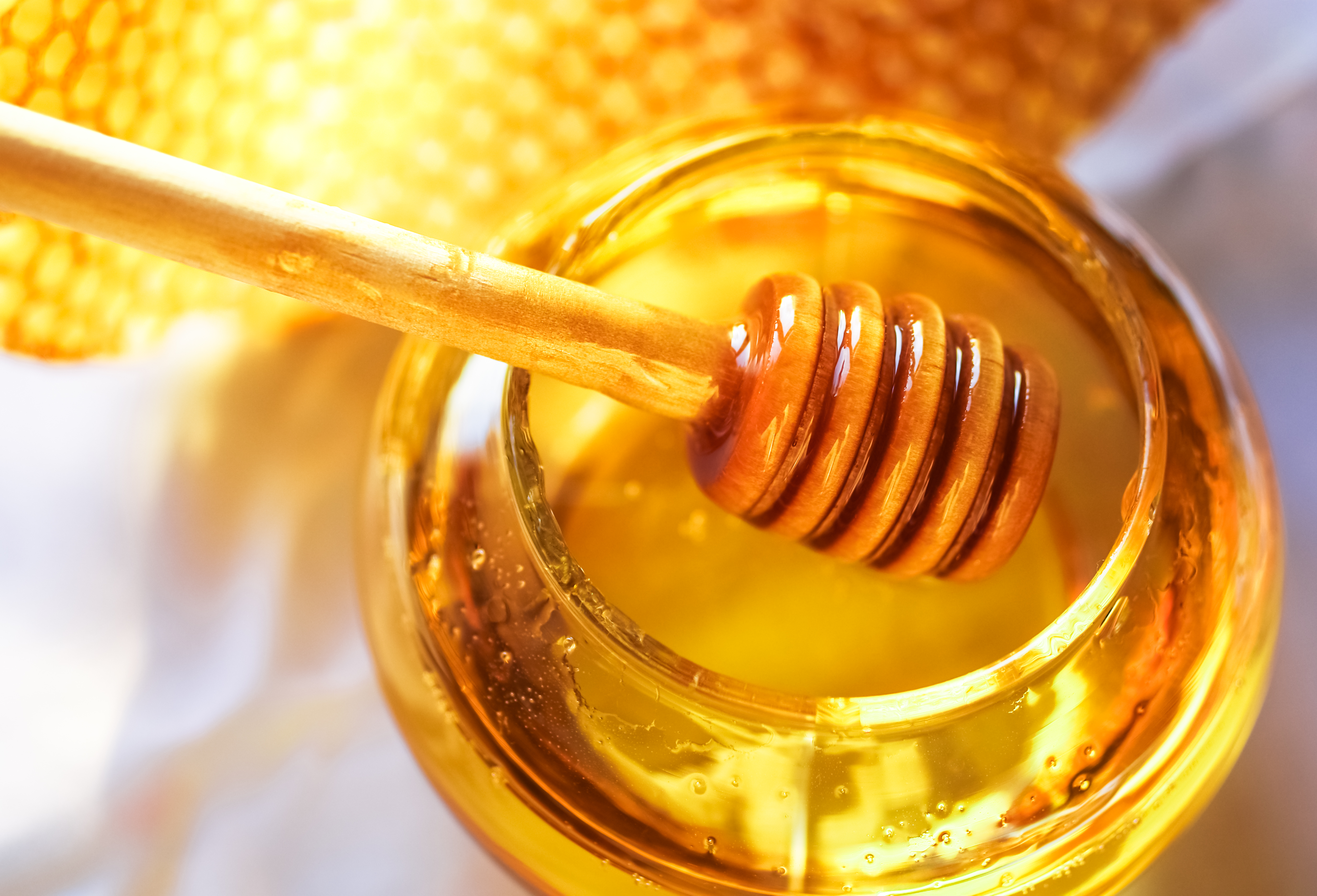 Honey dipper plunging into a jar of honey 