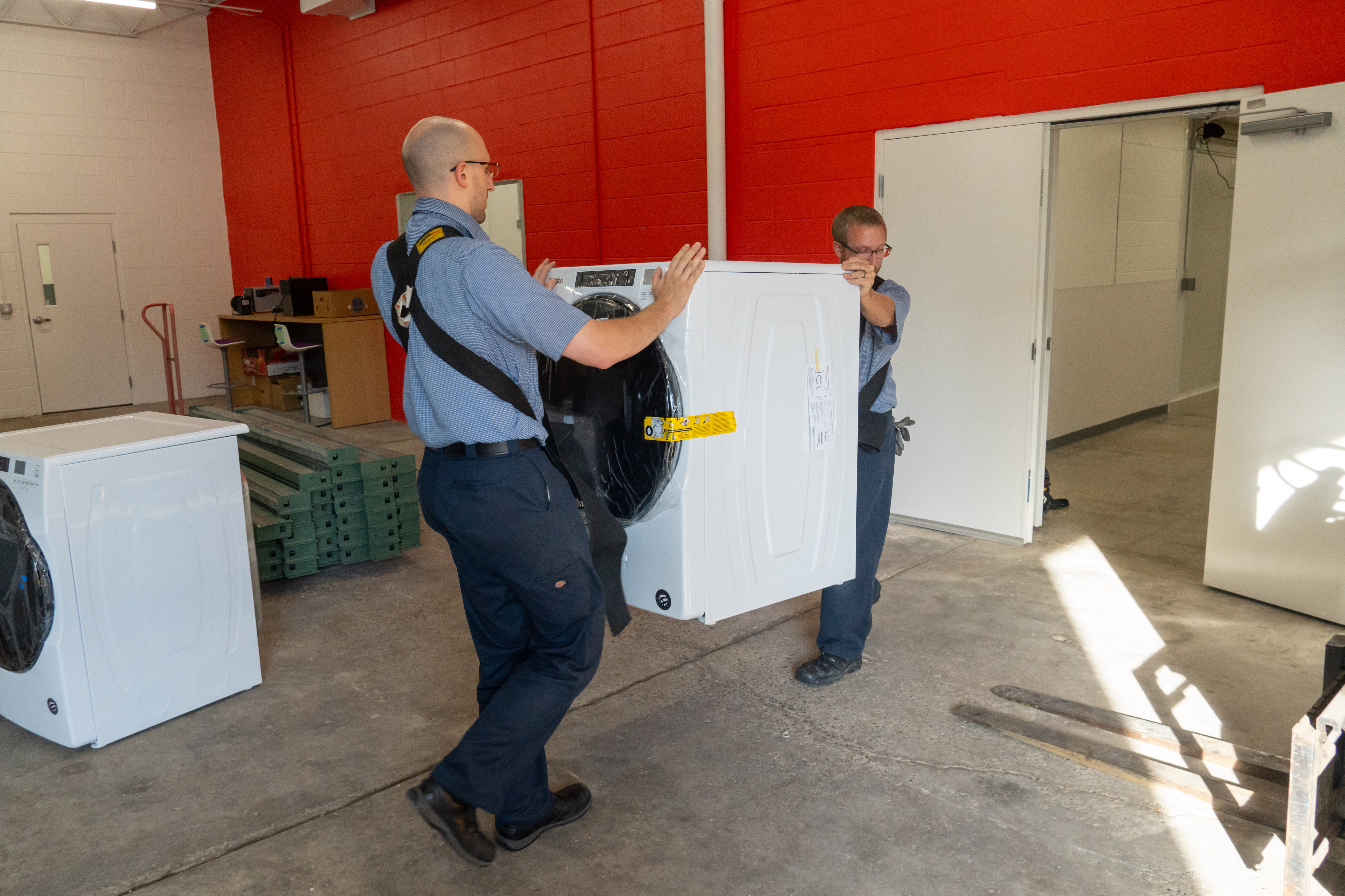 Professional installers carrying in a front load washing machine