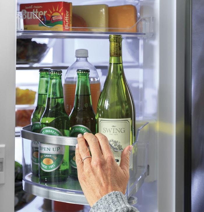 Hand reaching into the fridge for a selection of beverages.