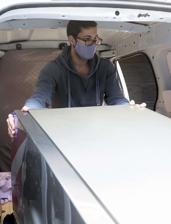 Man loading a fridge into a van.