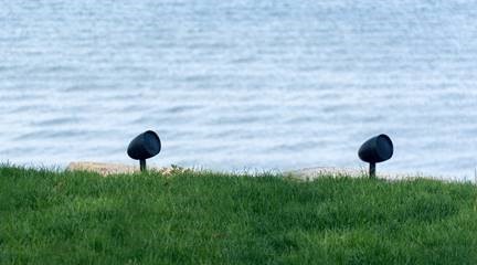A pair of solar powered lights by the water. 