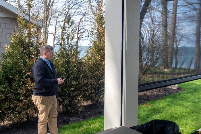 Tech installer standing outside of a nice, modern home. 