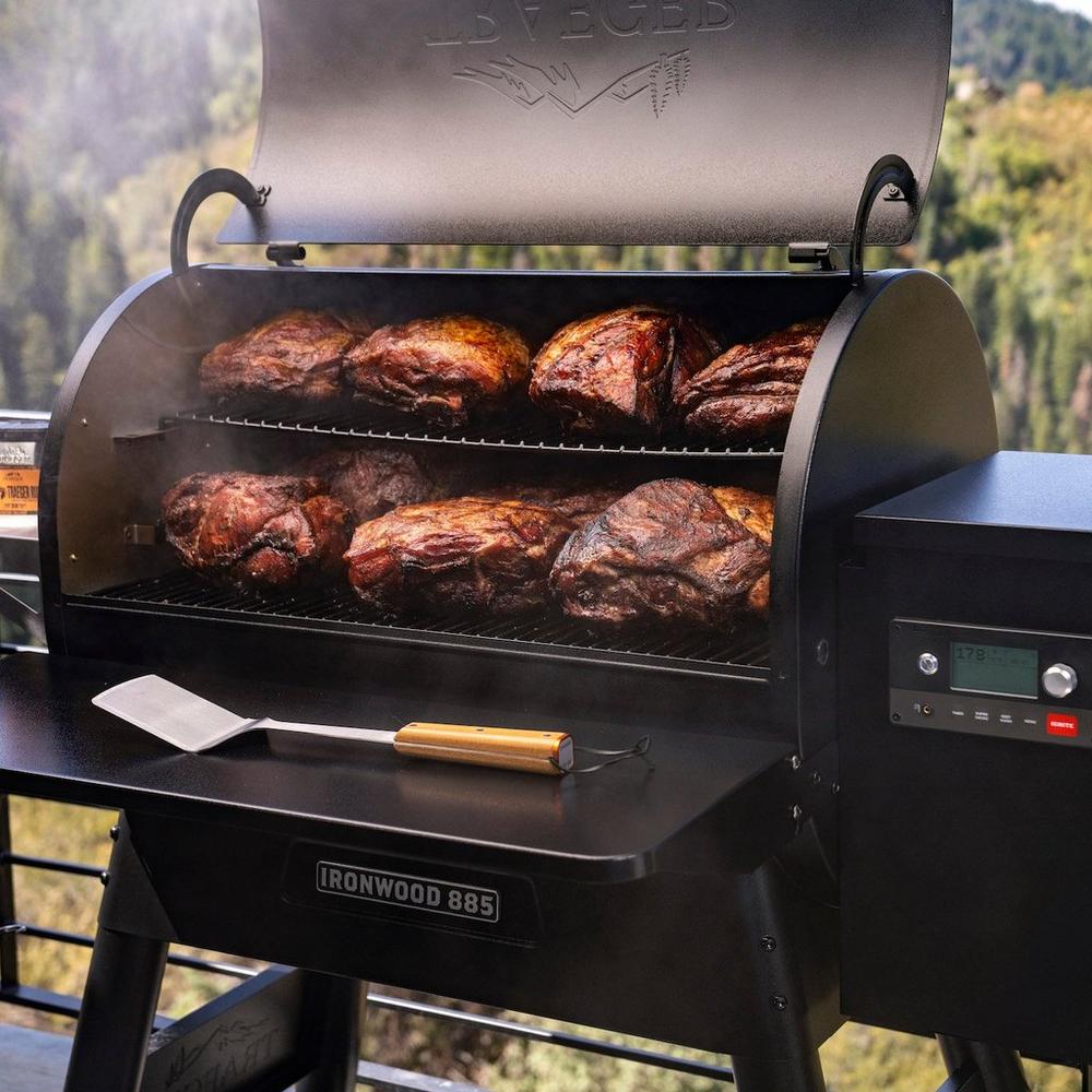 Traeger grill with lid open showing off several different roasts of meat.