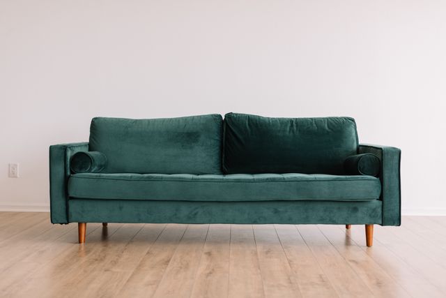 front view of a green velvet sofa in a modern living room