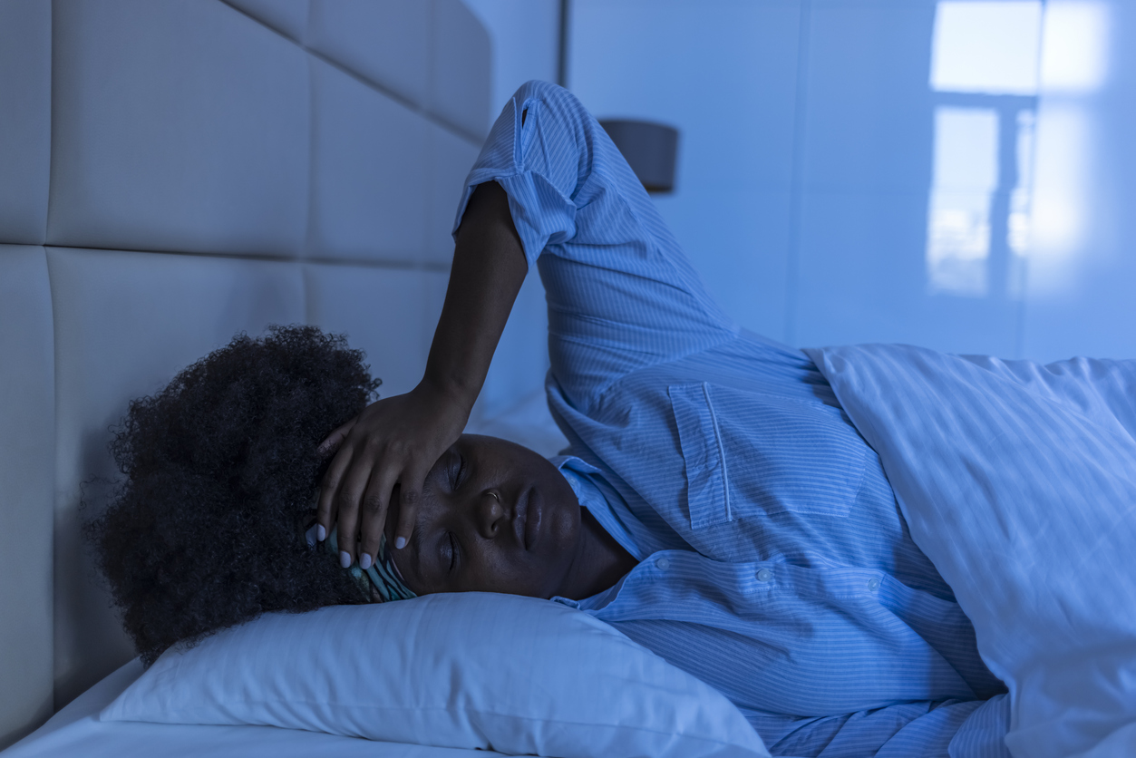 Woman in bed with hand on her head in frustration. 
