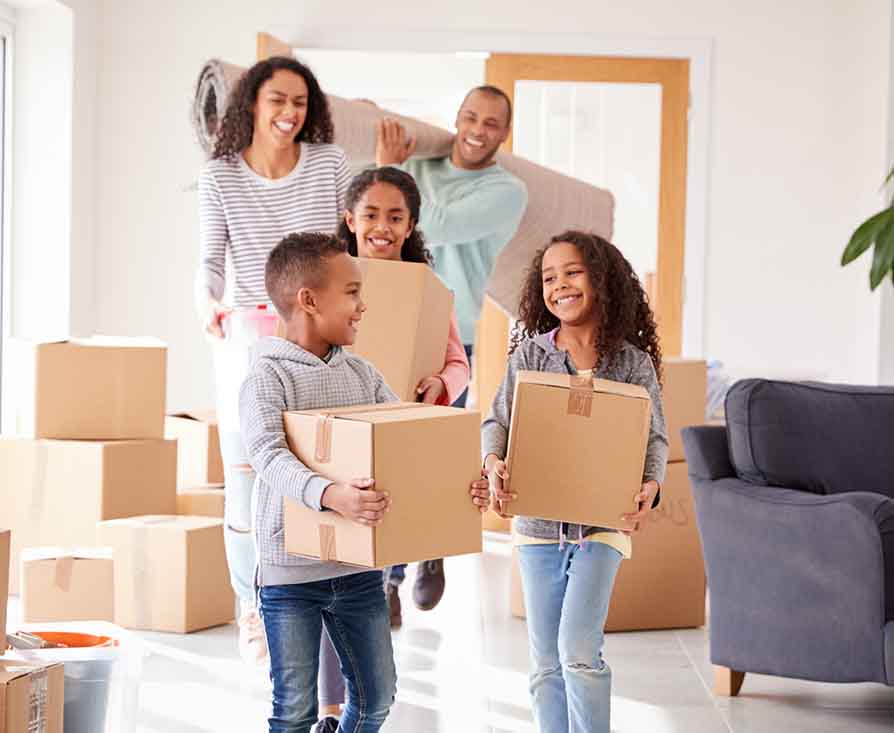 two parents and three kids moving boxes into their new home