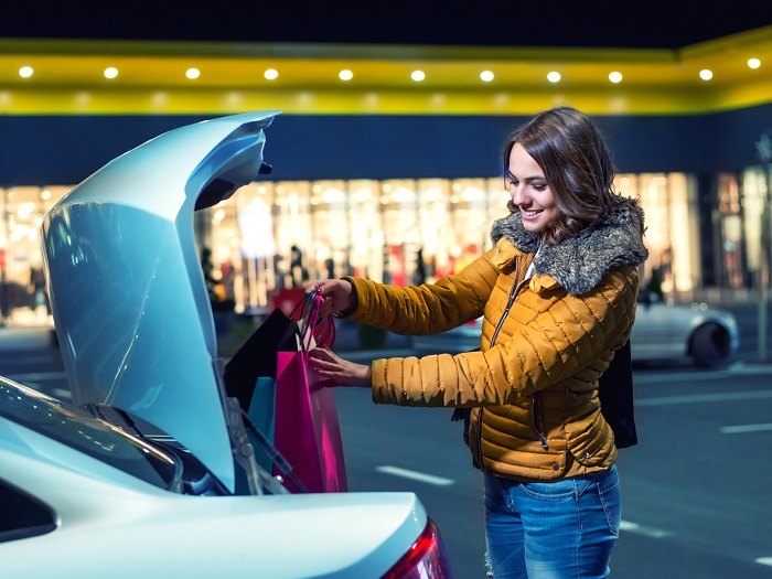 Young Woman putting shopping bags in the car.