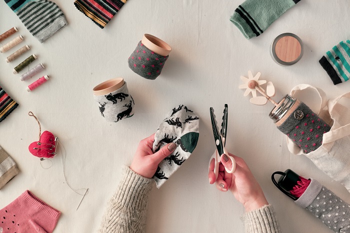 A woman with scissors making arts and crafts with reused socks. 