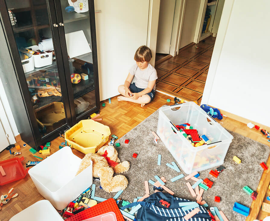 child with toys strewn on the floor 
