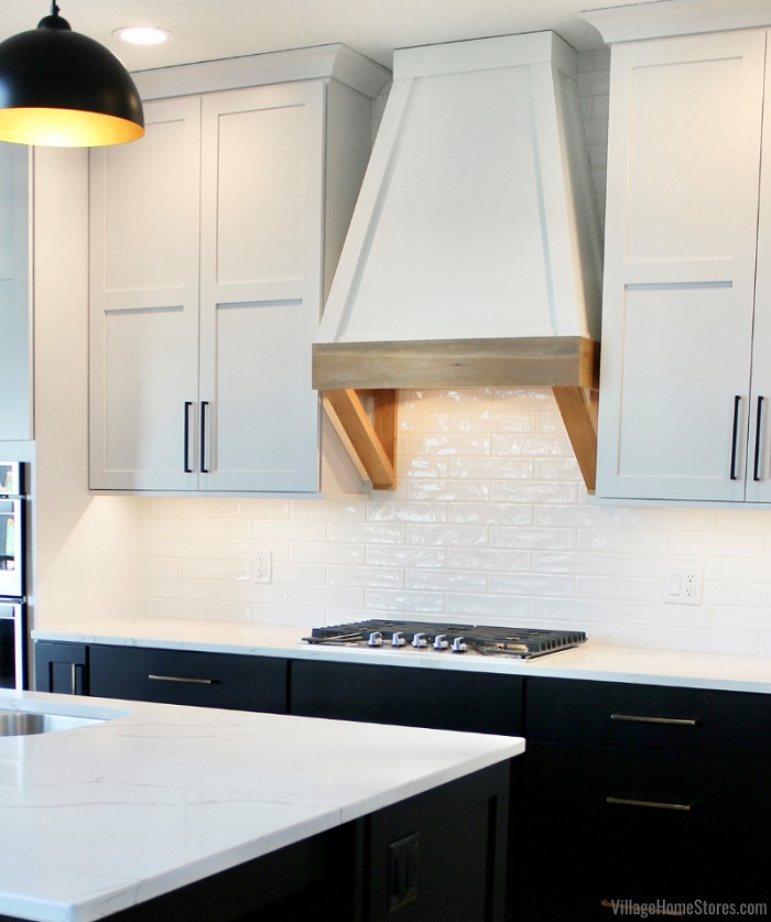 kitchen with black base cabinets and island and white upper cabinets. Long handle hardware in two finishes also featured