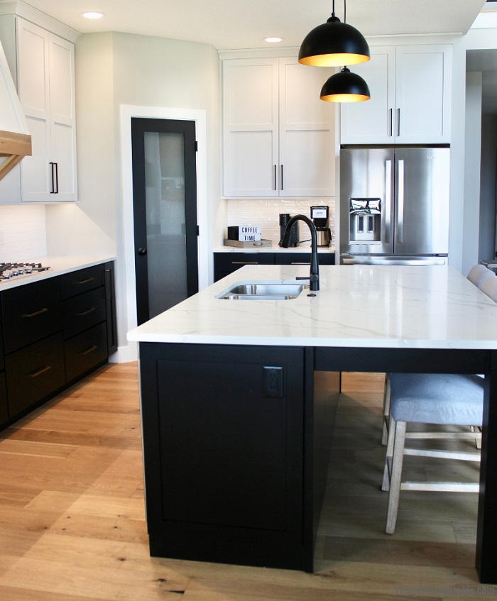 profile view of black painted kitchen island with deep countertop overhang and square furniture leg supports