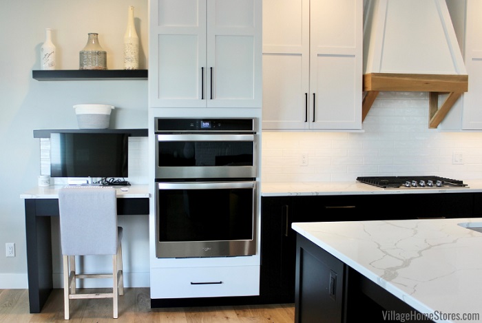 combination wall oven and microwave installed in tall cabinet next to desk area in kitchen with floating shelves