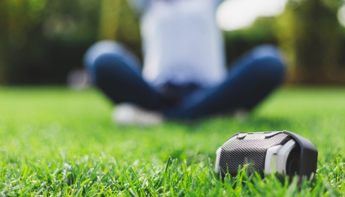 Closeup of someone listening to portable speaker in the park