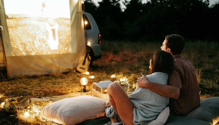 A couple watching a movie on a portable projector while camping