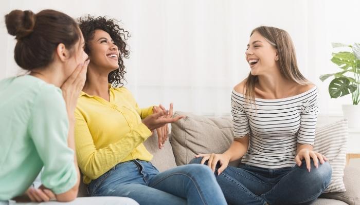 4 women talking and laughing together on a couch