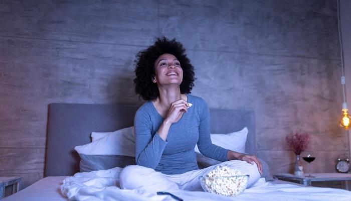 Woman in PJ’s watching movies & eating popcorn