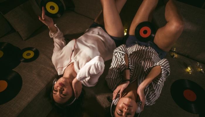 Two woman listening to record player, vinyls all around