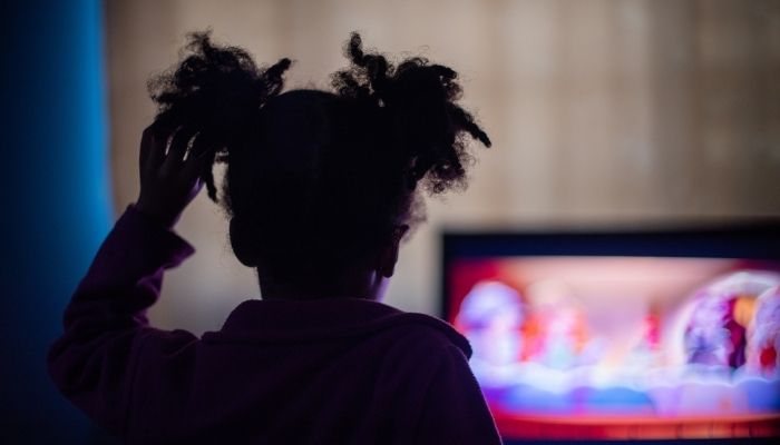 little girl watching TV in the dark