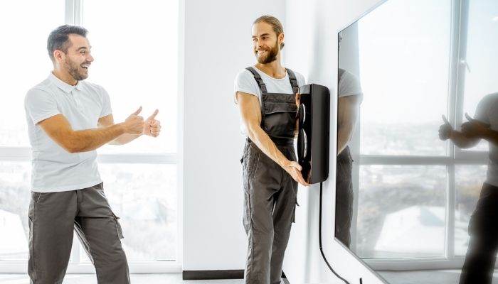 two men placing a speaker in the living room