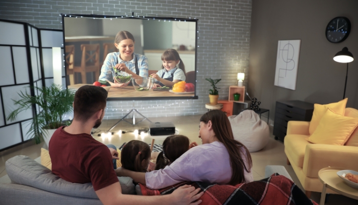 Family gathered for movie night with string lights and a bright picture