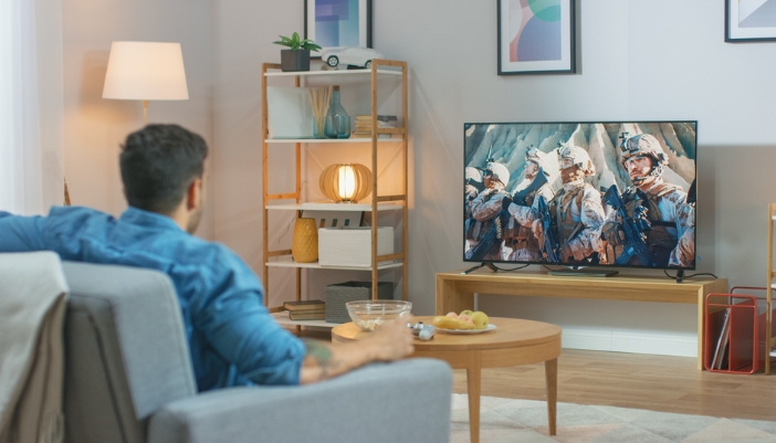 A man sits in his living room and watches a movie on TV.