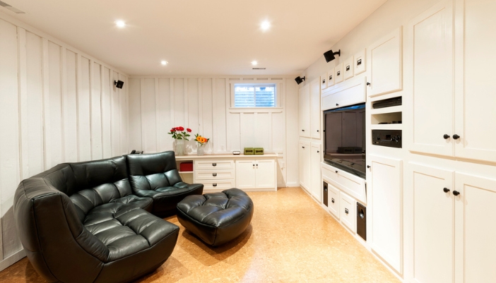 A brightly lit home theater with black leather furniture.