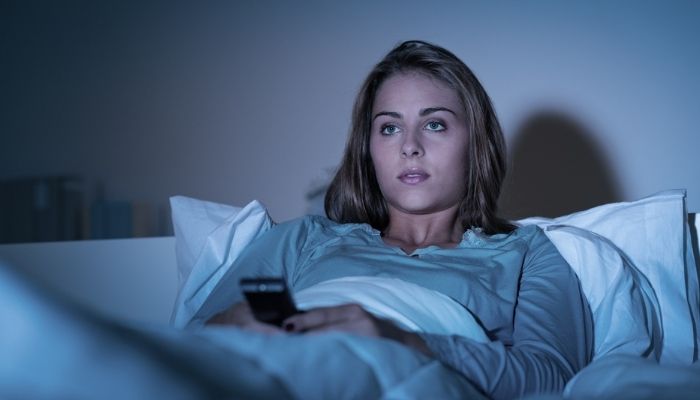 woman relaxing in bed watching tv