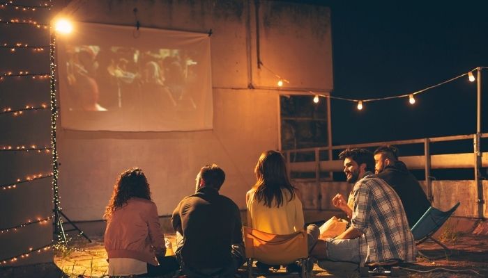 Group of young friends watching a movie on a building rooftop