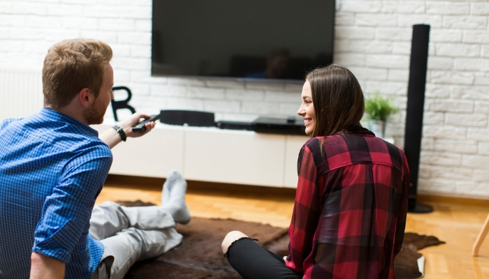 Couple about to watch TV with a soundbar and floorstanding speakers