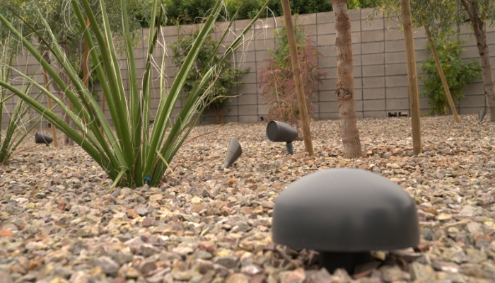 Closeup of buried subwoofer with satellite speakers in the background